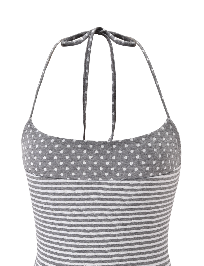 The DASHIELL TOP by TIGERMIST is a heather grey rib knit halter top with adjustable neck ties, featuring white polka dots on the upper section and horizontal white stripes on the lower part.
