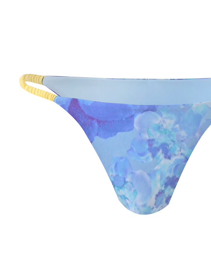 The TIGERMIST EMBERLAIN BIKINI BOTTOM - BLUE MACRO FLORAL features yellow and white double side straps and a blue floral print, shown on a white background.