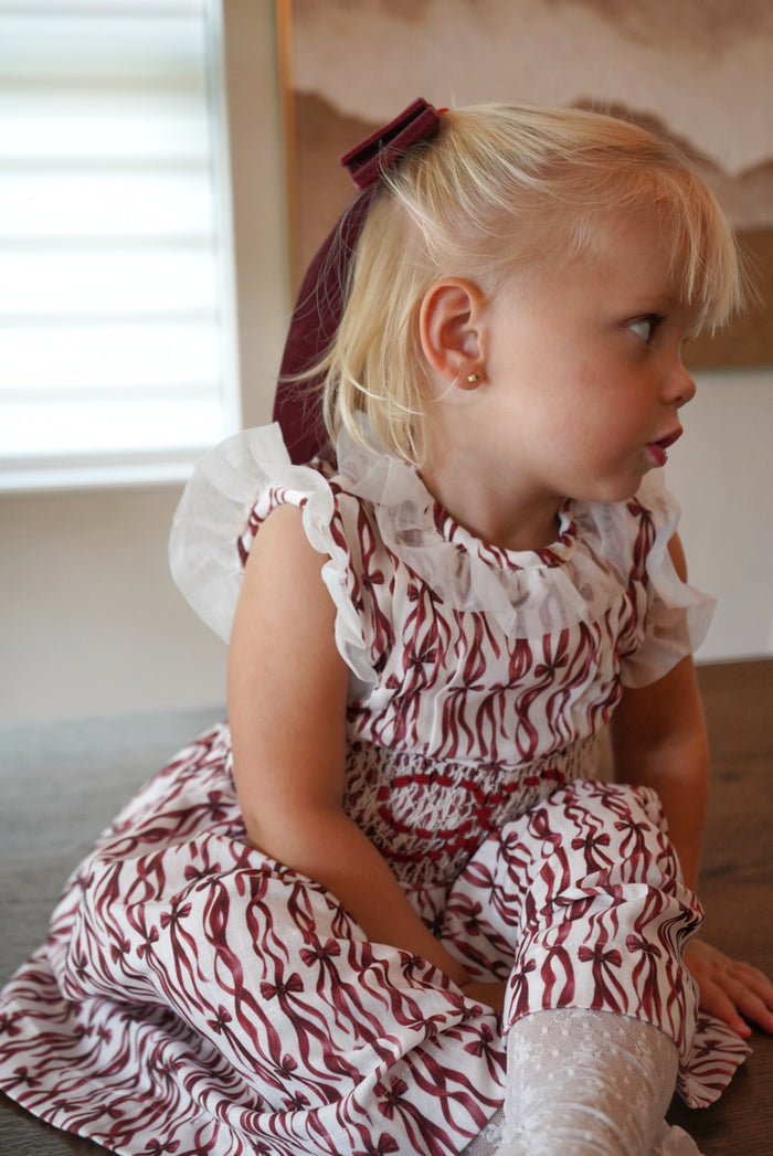 Girl wearing burgundy ribbon print Christmas dress