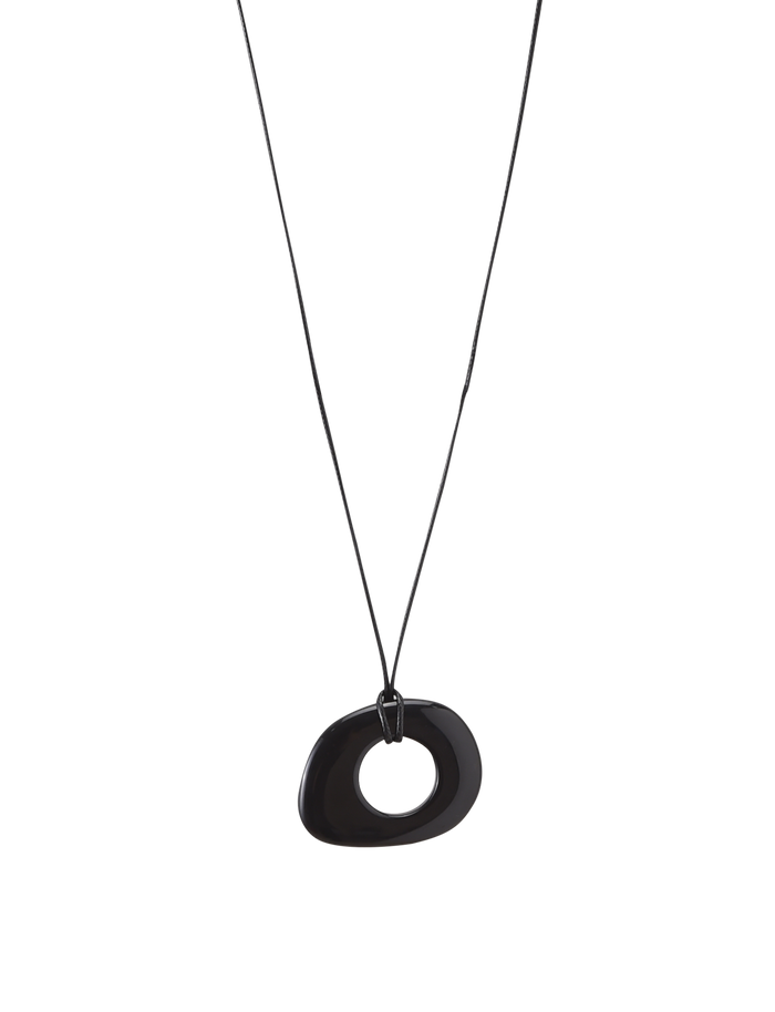 The FAELLA PENDANT NECKLACE - BLACK by TIGERMIST is a minimalist piece featuring a black cord and an asymmetrical, hollow oval resin pendant, shown against a plain white background.