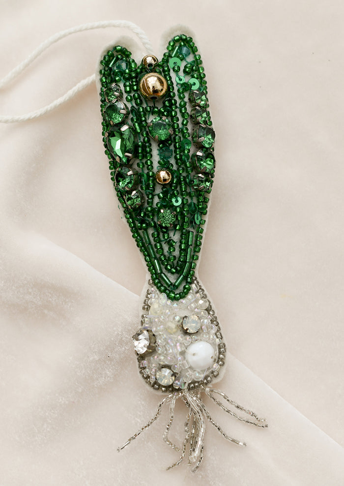 A felt ornament in shape of a green scallion, decorated with beads and sequins.