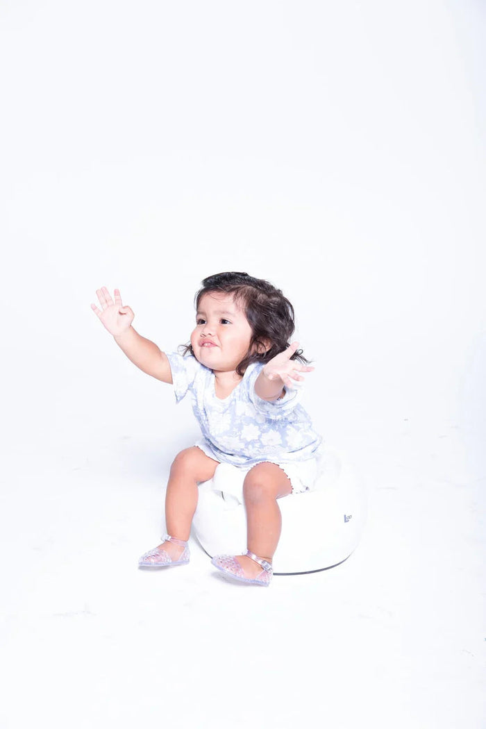 Toddler girl with outstretched arms using Joovy Loo Potty, perfect for Toshi Baby and baby strollers