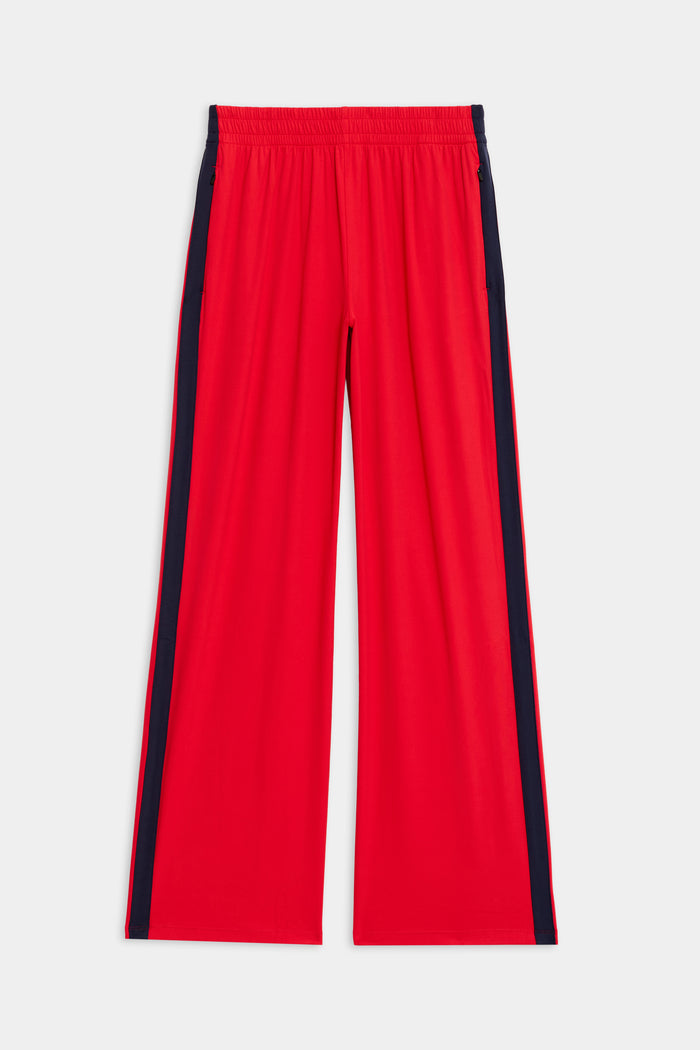 The Maxie Rigor Track Pant by SPLITS59 in Pirate Red/Indigo has a wide-leg design with an elastic waistband, sleek black side stripes, and is crafted from premium Rigor fabric, showcased flat on a white background.