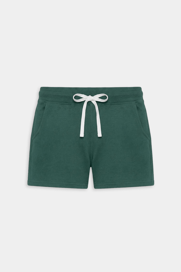 The SPLITS59 Reena Fleece Sweatshort in Arugula is a dark green mid-rise style made from ultra luxe fleece, featuring an elastic waistband, white drawstring, and two side pockets—ideal for cool weather workouts.