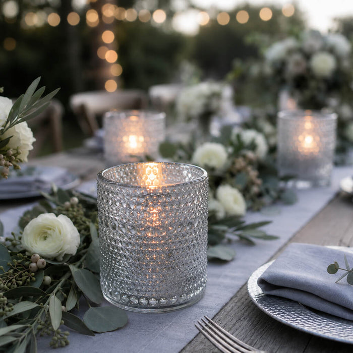 Pearly silver candle holder glowing on an elegant outdoor table with white flowers