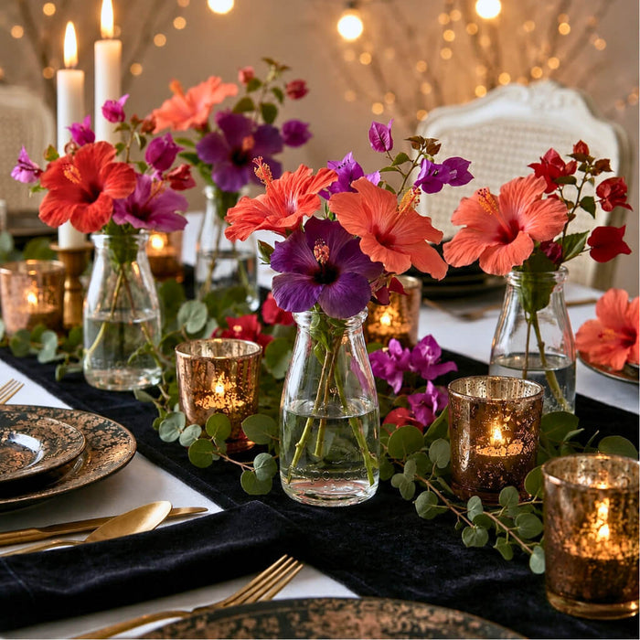 Rhea Bud Vase containing vibrant hibiscus flowers on a dark table runner with gold accents