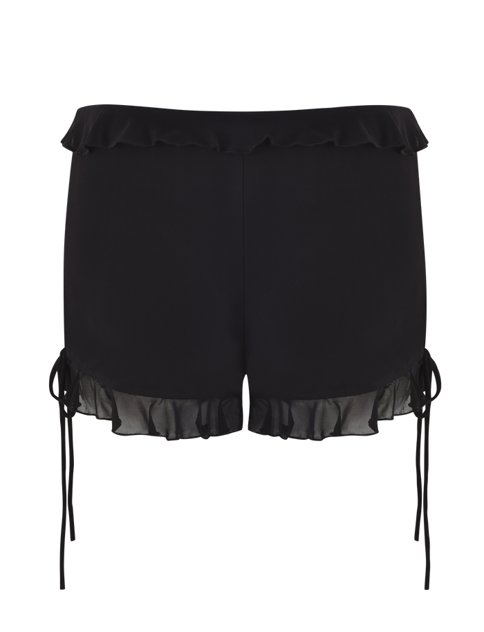 The SIERA SHORT - BLACK by TIGERMIST features high-waisted black mesh fabric, ruffled trim at the waistband and hem, and side ties. These bodycon shorts are styled for a feminine look and shown photographed from the back.