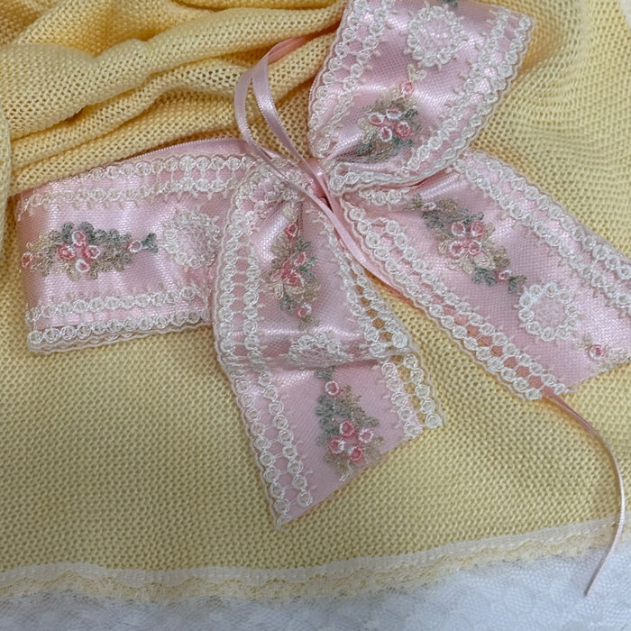 Close-up of pink floral bow and ivory lace detailing on Aida Rose Luxe Yellow Blanket