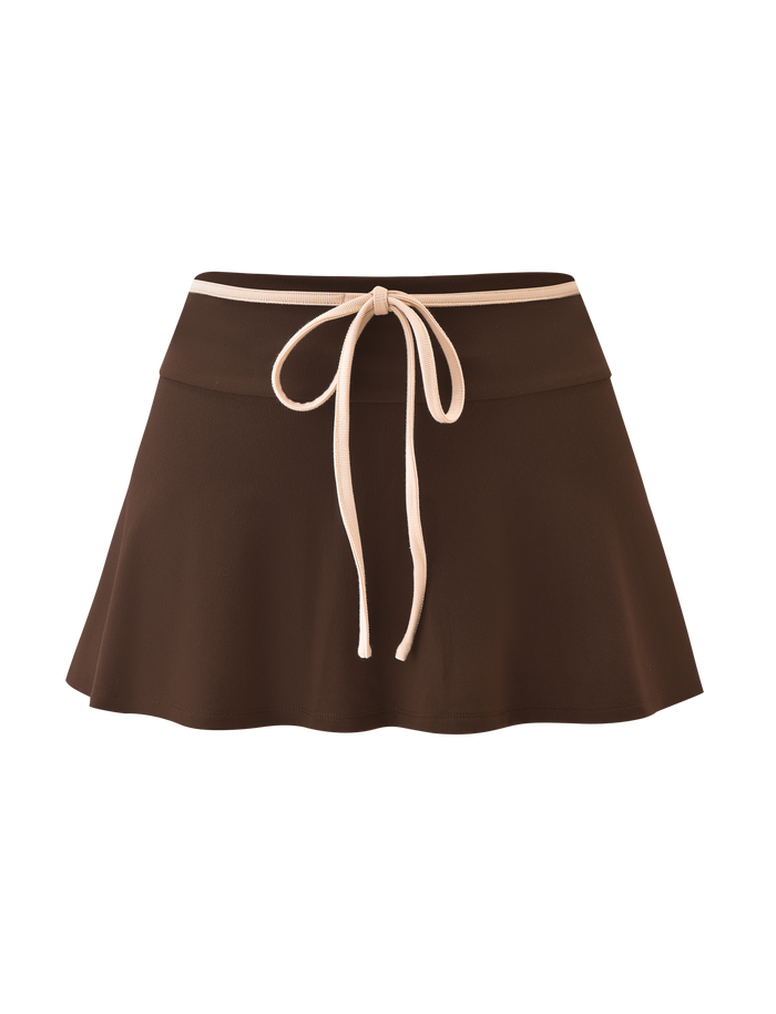 The TIGERMIST ALYSIA SKORT - CHOCOLATE is a brown A-line mini skort featuring a flared hem and a beige drawstring bow at the wide waistband.