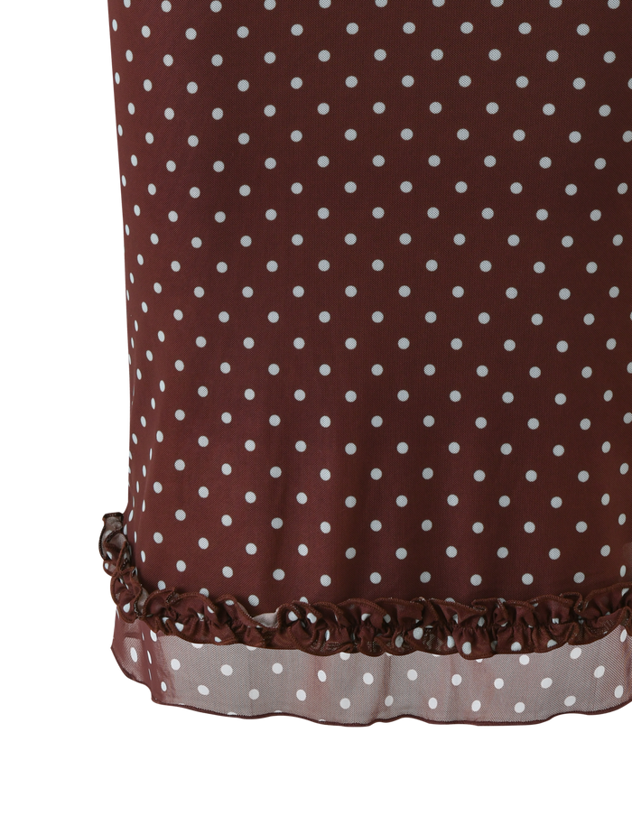 Close-up of the TIGERMIST AMARA MIDI SKIRT - POLKA DOT, showcasing its brown fabric with white spots, ruffled hem, and a slightly sheer lace trim near the edge.