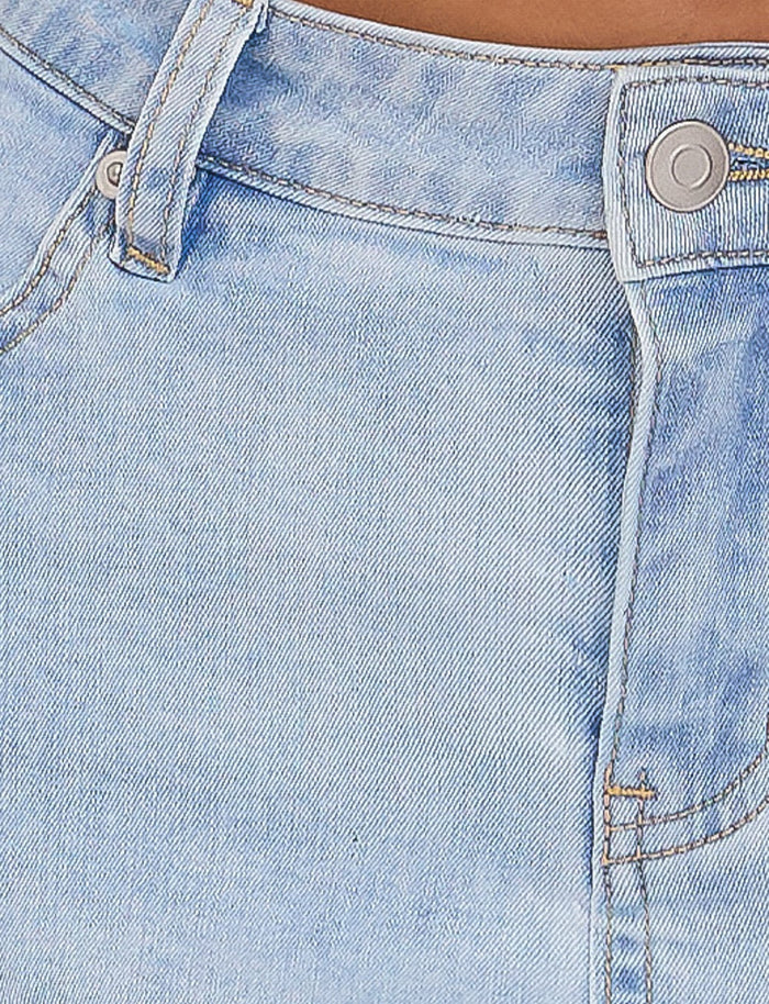 Close-up of a person wearing the light-wash blue AMAYA MINI SKIRT by TIGERMIST. The image focuses on the waistband, belt loop, button closure, and fly area, highlighting the texture and stitching details of the fabric.