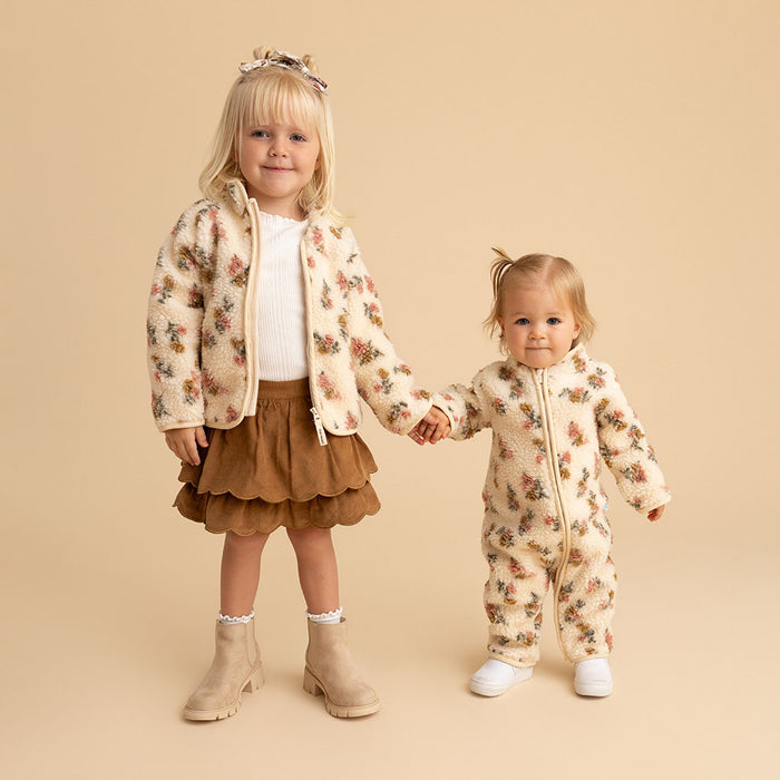 Two children walking hand-in-hand, wearing matching Amber print outerwear