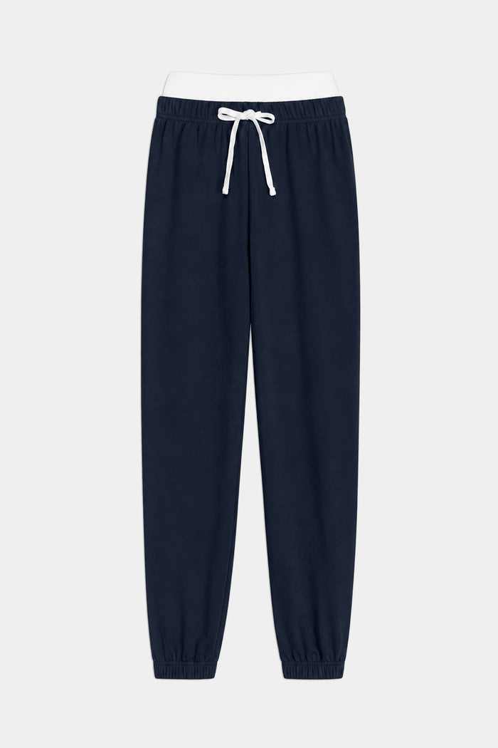 The SPLITS59 Andie Dual Waist Sweatpant in Indigo/White is crafted from ultra-luxe fleece with an elastic waistband, white drawstring, and elastic cuffs, shown laid flat on a white background. Made in Los Angeles.