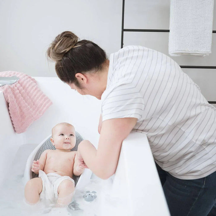 Baby in a bath seat using Angelcare Bath Support with Toshi Baby Romper and Odyssey Wagon Wheels style