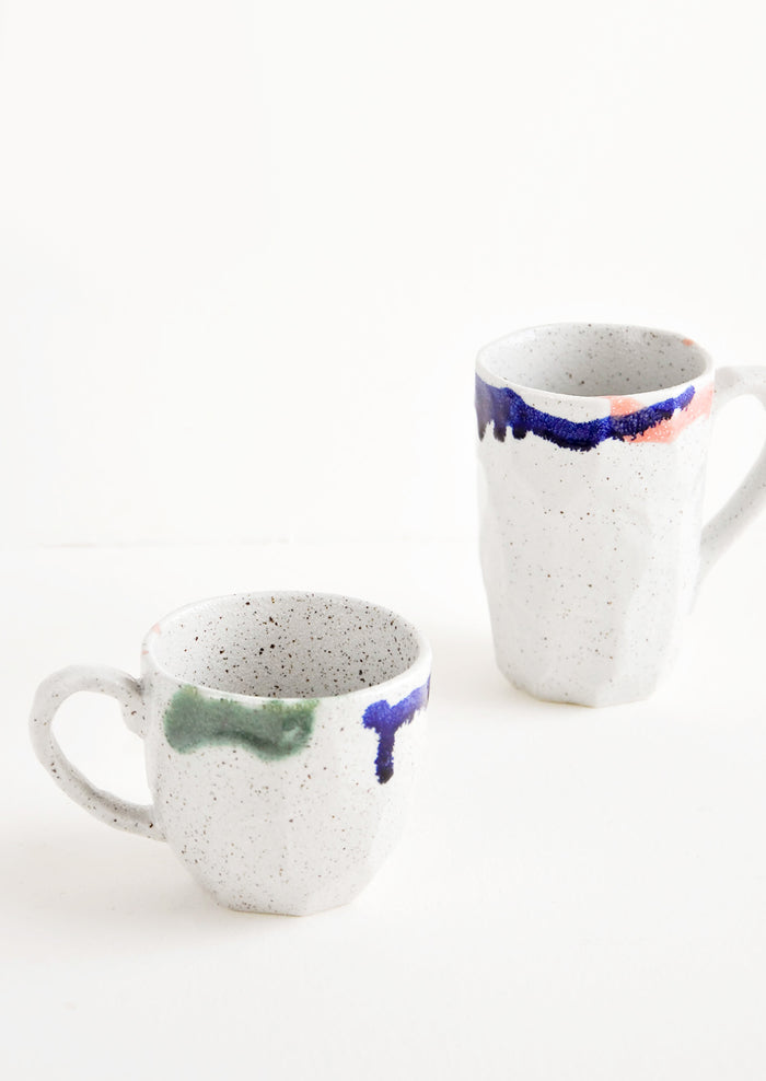 Two differently sized gray ceramic mugs with blue, green, and pink painted rims.