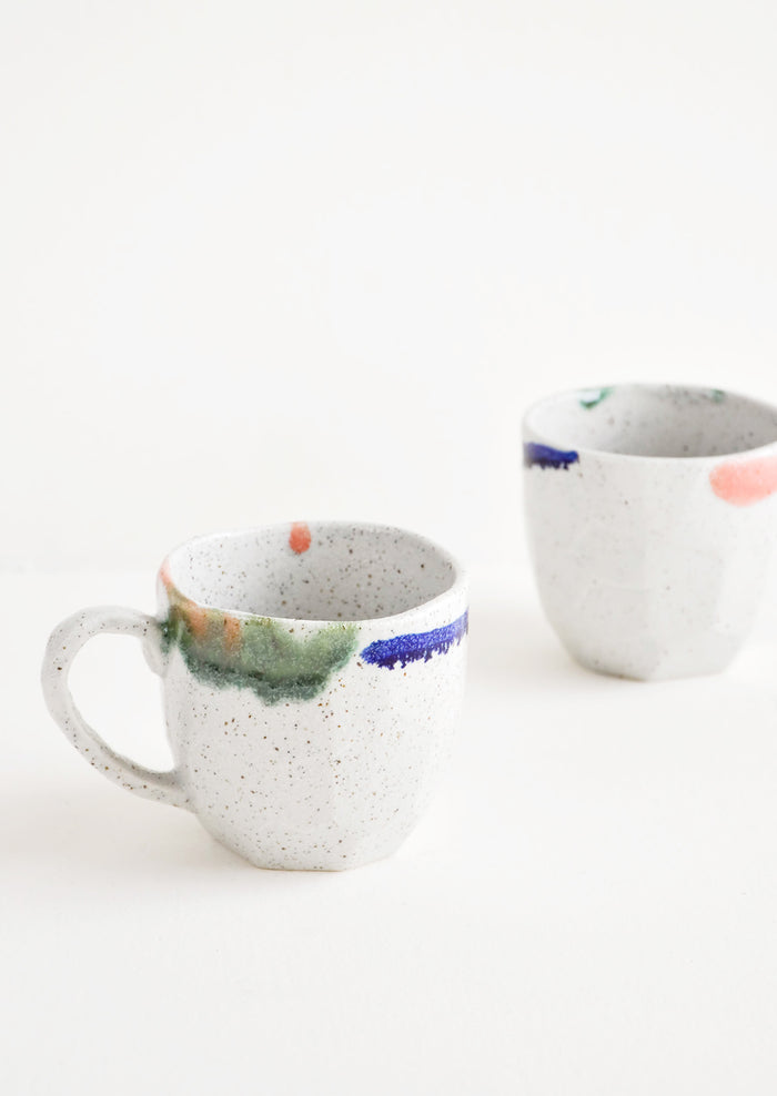 Two short gray ceramic mugs with blue, green, and pink painted rims.