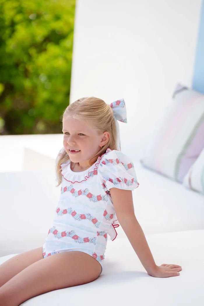 Girl wearing Breeze Floral Swimsuit in coral floral-and-bow print