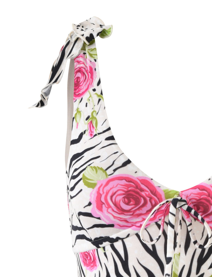 A close-up of the TIGERMIST BRYNNE DRESS - MULTI : ZEBRA, showcasing its zebra print pattern adorned with pink roses. The dress features a neckline with adjustable tie straps on the shoulders, blending black and white stripes with vibrant pink floral accents.