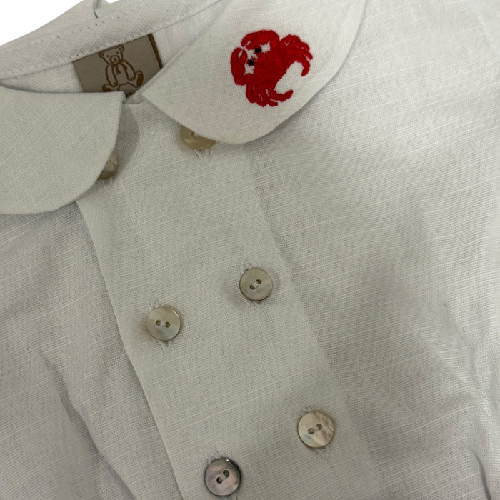 Close-up of embroidered red crab, rounded collar and button detailing on Crab Boy shirt