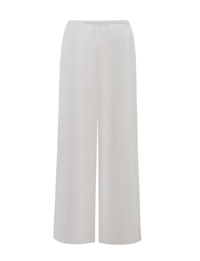 The TIGERMIST CRESSY PANT - WHITE is a full-length, wide-leg cotton pant featuring a high waist, elastic waistband, and subtle leg embroidery, shown against a plain white background.