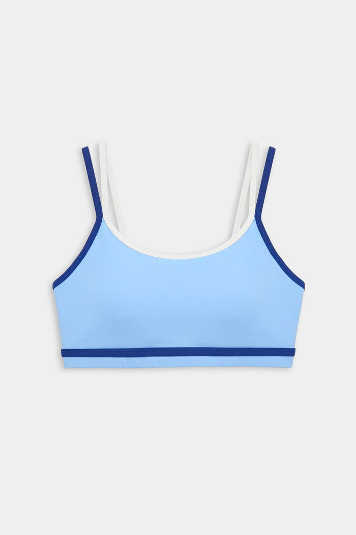 The SPLITS59 Eva Rigor Double Strap Bra in Skylight/Cobalt features light blue fabric with dark blue trim and white double straps, perfect for the gym, displayed against a plain white background.