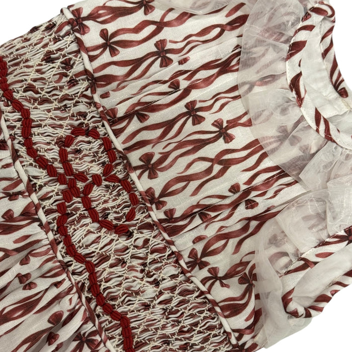 Close-up of burgundy ribbon print and ruffled shoulder detailing
