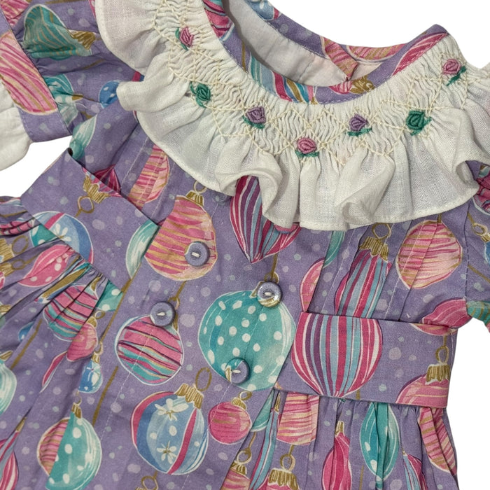 Close-up of pastel Christmas ornament print and handsmocked bodice detailing