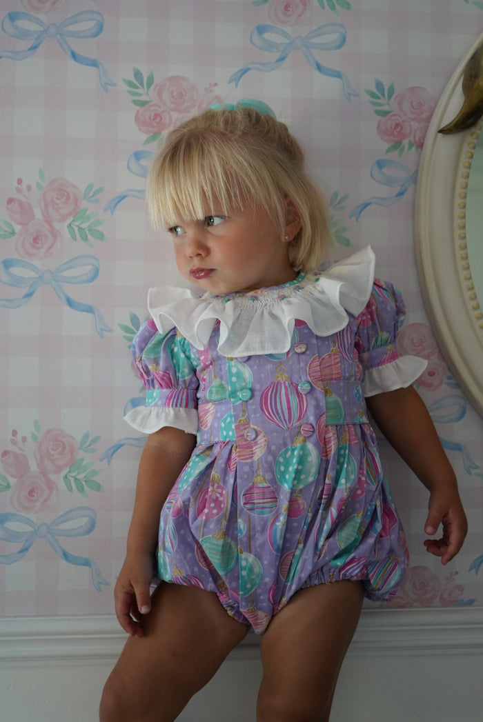Side view of girl wearing Gigi Ornaments Pastels Handsmocked Romper
