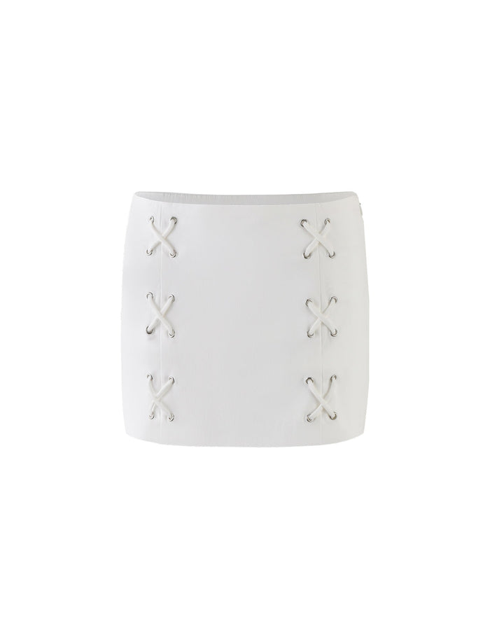The HALSEY SKIRT - WHITE : CREAM from TIGERMIST is a stylish mini skirt featuring decorative crisscross lacing details on both sides. The laces are threaded through metal eyelets arranged in pairs, creating an X pattern, and the skirt has a simple, modern design with a straight-cut hem.