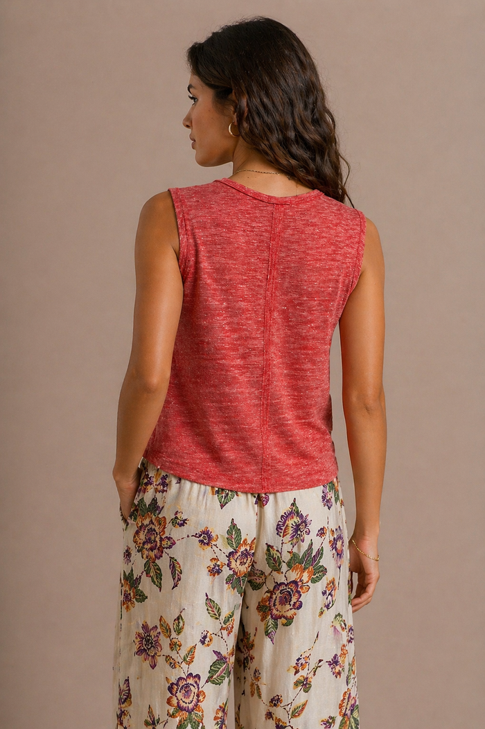 Woman wearing a red sleeveless top and floral pants against a beige background