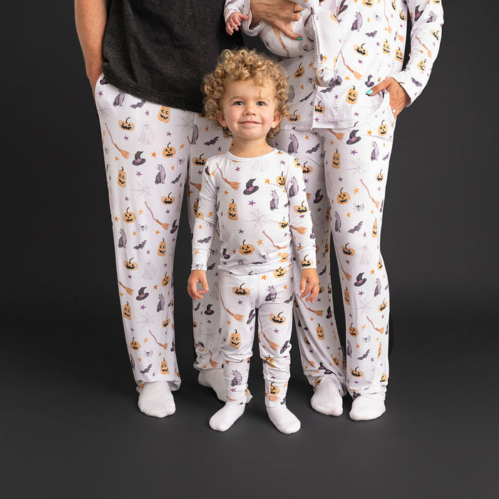 Child standing with family members, wearing the Posh Peanut Irving Classic Pajama Set, dark background.