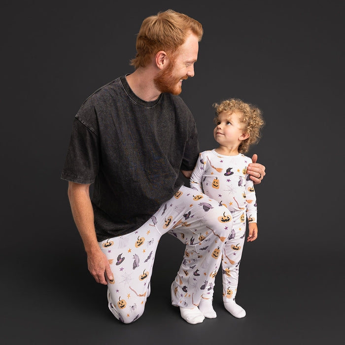 A father kneeling with a child, both wearing coordinating Posh Peanut Irving pajamas.