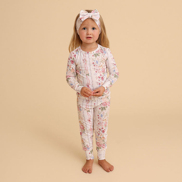 Girl standing wearing the Janey print classic pajama set with a headband, on a cream background