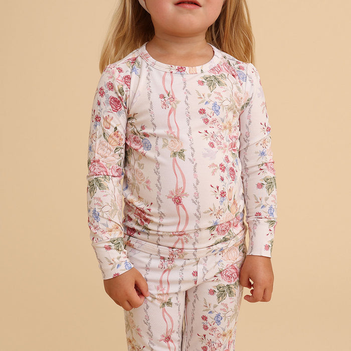 Girl sitting wearing the Janey print classic pajama set, on a cream background
