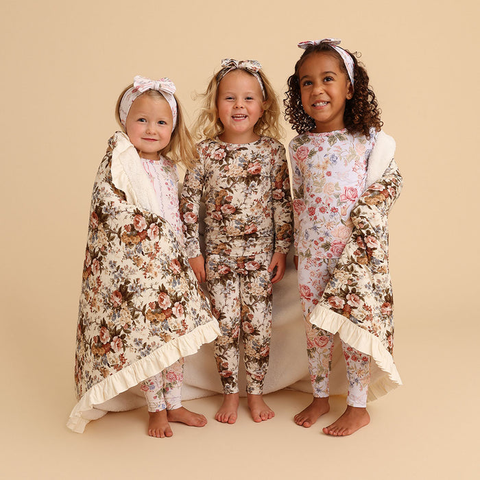Family standing together outdoors in a grassy field, all wearing matching Janey print pajama sets