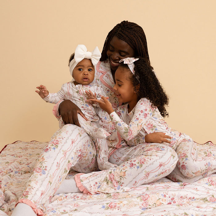 Mother holding baby, both dressed in coordinating Janey print pieces, sitting on a bed