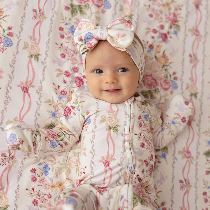 Baby wearing the Janey print luxe bow headwrap, sitting on a tan background
