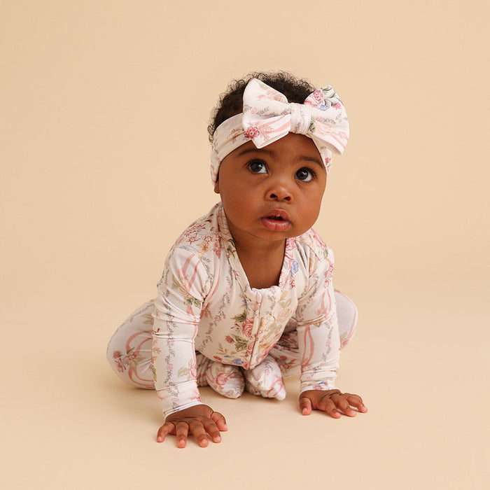 Baby crawling while wearing the Janey print luxe bow headwrap, on a tan background
