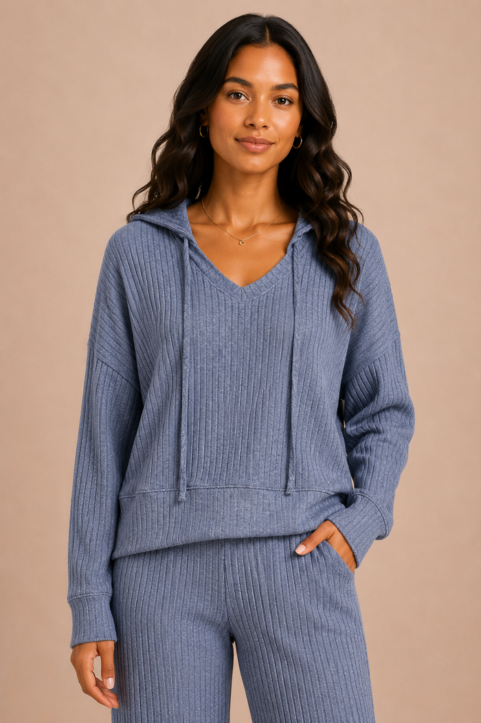 Woman wearing a blue ribbed hoodie and pants on a beige background