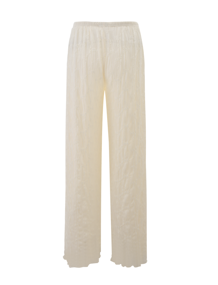 The KATERINA PANT - IVORY LACE by TIGERMIST features wide legs, a high waist, an elasticated band, and a delicate floral lace pattern, shown here in cream against a white background.