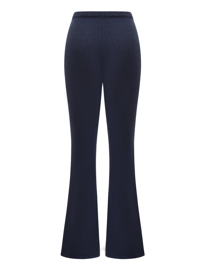 Back view of LEORA PANT - NAVY by TIGERMIST: dark navy blue, high-waisted relaxed knit pants with a flared silhouette and drawstring waist, shown against a white background.