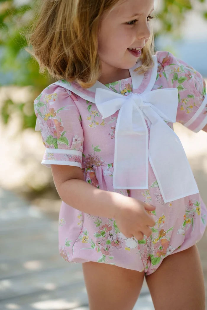 Girl wearing pink floral sailor romper with oversized white bow