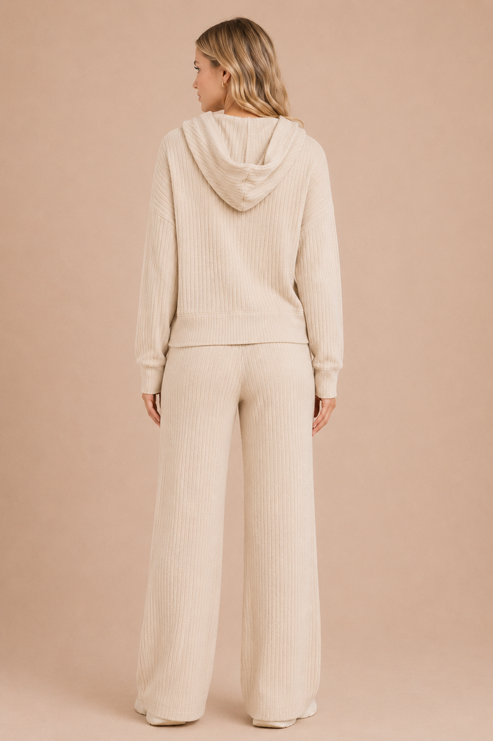Woman wearing a beige ribbed hoodie and pants on a beige background