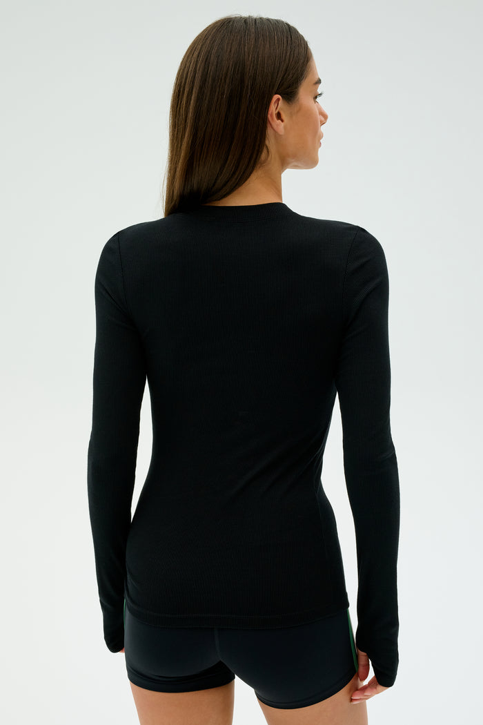 Individual wearing a black Louise Rib Long Sleeve from SPLITS59 and shorts, facing away against a plain background. Crafted in Los Angeles.