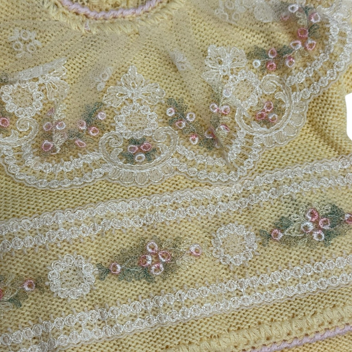 Close-up of pink floral embroidery and ivory lace on Aida Yellow knitted set