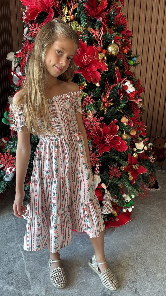 Girl wearing Piccoli & Co Christmas nap dress beside a decorated Christmas tree