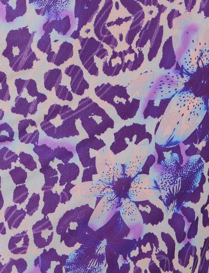 The MAGDALENA MAXI DRESS - PURPLE by TIGERMIST features a vibrant pattern that blends purple leopard spots with large light pink lilies, accented in purple. The intricately woven lilies and spots create a bold and dynamic design.