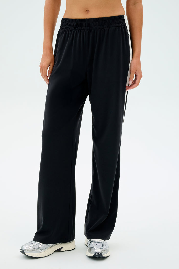 Individual wearing SPLITS59 Maxie Rigor Track Pant in Black/White paired with white sneakers against a plain background.