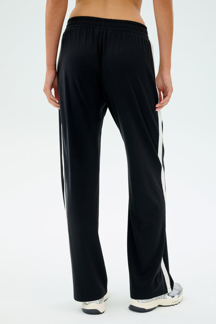 Someone wearing SPLITS59's Maxie Rigor Track Pant - Black/White is standing with their back to the camera.
