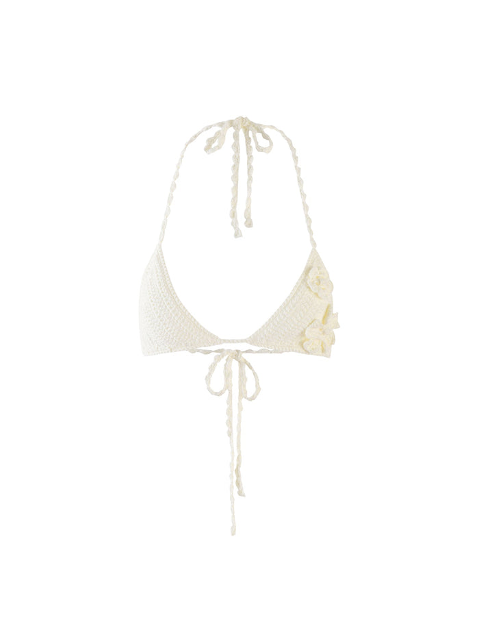 The MELIORA BIKINI TOP - WHITE by TIGERMIST is displayed against a plain background. This white crocheted bikini top features a halter neck tie and a tie closure at the front, with three small, crocheted flower appliqués adorning the right side.